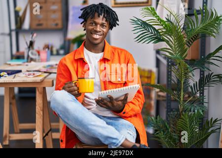 Un artiste afro-américain qui boit du café attire un studio d'art Banque D'Images