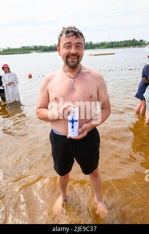 Norderstedt, Allemagne. 26th juin 2022. Baptisé Mirko hein (49), se tient avec une bougie baptismale dans le Stadtparksee après son baptême. Un baptême de masse avec 57 participants et environ 500 invités a été célébré par sept congrégations d'église à et dans le Stadtparksee à Norderstedt près de Hambourg. Credit: Jonas Walzberg/dpa/Alay Live News Banque D'Images