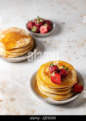 Petit déjeuner américain classique de style rustique. Crêpes maison avec fraise et miel sur la table de cuisine. Orientation verticale Banque D'Images