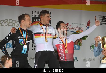 Winterberg, Allemagne. 26th juin 2022. Cyclisme: Championnat allemand: Arnsberg - Winterberg (210,00 km): Simon Geschke (r) troisième placé de Team Cofidis prend un selfie avec le gagnant Nils Politt (M) de Bora - hansgrohe et Nikias Arndt deuxième placé de Team DSM après la cérémonie de prix, en collant sa langue. Devant, le filleul d'Arndt, qu'il avait emmené sur le podium avec lui. Credit: Bernd Thissen/dpa/Alay Live News Banque D'Images