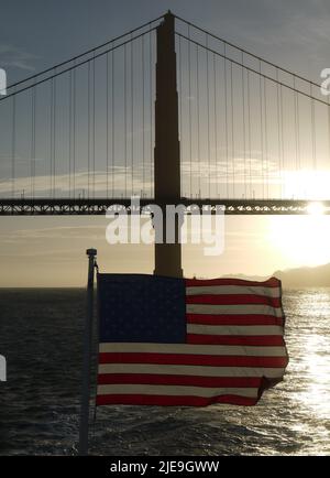 Coucher de soleil sur le Golden Gate Bridge avec drapeau américain au premier plan Banque D'Images