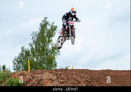 Dobele, Lettonie, 18 juin 2022: Le coureur de motocross en vol, saute et déchaîne sur un tremplin contre le ciel Banque D'Images