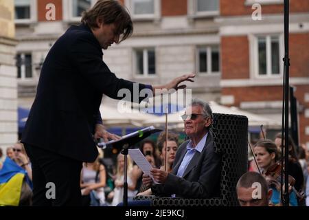 Sir Michael Palin (à droite) est le narrateur d'une représentation de Peter et du Loup, par le compositeur ukrainien Sergey Prokofiev, avec le Playing for Peace Orchestra - qui présente le chef d'orchestre anglo-russe Petr Limonov (à gauche), le violoniste ukrainien Corey Sheldunov, âgé de 11 ans, Et le petit-fils du compositeur Gabriel Prokofiev sur la Corne de France - en face de l'église St Paul, Covent Garden, centre de Londres. Les musiciens du Playing for Peace Orchestra sont issus des meilleurs orchestres de Londres et la représentation collecte des fonds pour l'appel humanitaire d'Ukraine du Comité d'urgence des catastrophes (DEC). Image Banque D'Images