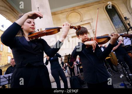 Corey Sheldunov (à droite), violoniste ukrainien de 11 ans, participe à une représentation de Peter et du Loup, du compositeur ukrainien Sergey Prokofiev, avec le Playing for Peace Orchestra - qui présente Sir Michael Palin comme narrateur, le chef d'orchestre anglo-russe Petr Limonov, Et le petit-fils du compositeur Gabriel Prokofiev sur la Corne de France - en face de l'église St Paul, Covent Garden, centre de Londres. Les musiciens du Playing for Peace Orchestra sont issus des meilleurs orchestres de Londres et la représentation collecte des fonds pour l'appel humanitaire d'Ukraine du Comité d'urgence des catastrophes (DEC). Image da Banque D'Images