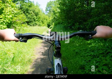 Vélo dans le parc de la ville. Vue à travers les yeux des motards. Mains sur le guidon d'une bicyclette gros plan Banque D'Images