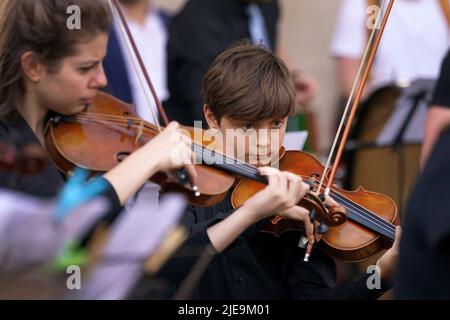 Corey Sheldunov (à droite), violoniste ukrainien de 11 ans, participe à une représentation de Peter et du Loup, du compositeur ukrainien Sergey Prokofiev, avec le Playing for Peace Orchestra - qui présente Sir Michael Palin comme narrateur, le chef d'orchestre anglo-russe Petr Limonov, Et le petit-fils du compositeur Gabriel Prokofiev sur la Corne de France - en face de l'église St Paul, Covent Garden, centre de Londres. Les musiciens du Playing for Peace Orchestra sont issus des meilleurs orchestres de Londres et la représentation collecte des fonds pour l'appel humanitaire d'Ukraine du Comité d'urgence des catastrophes (DEC). Image da Banque D'Images