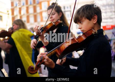 Corey Sheldunov (à droite), violoniste ukrainien de 11 ans, participe à une représentation de Peter et du Loup, du compositeur ukrainien Sergey Prokofiev, avec le Playing for Peace Orchestra - qui présente Sir Michael Palin comme narrateur, le chef d'orchestre anglo-russe Petr Limonov, Et le petit-fils du compositeur Gabriel Prokofiev sur la Corne de France - en face de l'église St Paul, Covent Garden, centre de Londres. Les musiciens du Playing for Peace Orchestra sont issus des meilleurs orchestres de Londres et la représentation collecte des fonds pour l'appel humanitaire d'Ukraine du Comité d'urgence des catastrophes (DEC). Image da Banque D'Images