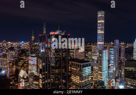Scène nocturne de la ville avec des bâtiments modernes de haute élévation dans la métropole. Façade en verre sombre brillant reflétant les lumières environnantes. Manhattan, New York, États-Unis Banque D'Images