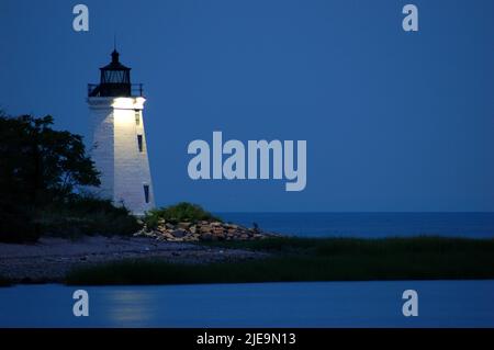 Le phare de Bridgeport, également connu sous le nom de Black Harbour Light, brille contre un ciel crépuscule le long de la plage de long Island Sound Banque D'Images