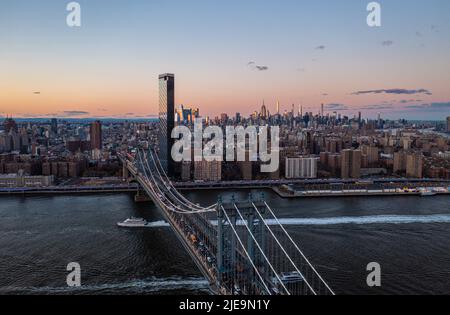 Vue aérienne des bateaux passant sous une route animée sur le pont de Manhattan. Horizon avec gratte-ciel contre ciel crépuscule. Manhattan, New York, États-Unis Banque D'Images