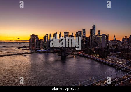 Les gratte-ciel du bas de Manhattan silhouettes contre le ciel coloré de coucher de soleil. Circulation dense sur les routes le long de l'eau. Manhattan, New York, États-Unis Banque D'Images