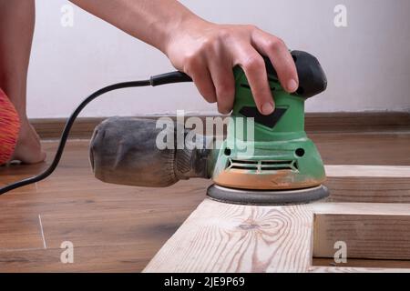 master traite les portes en bois avec un outil de meulage, restauration, préparation de la porte pour la peinture, nettoyage de la surface du bois. Banque D'Images