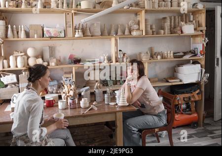 les filles artisanales sont assises à une table dans un atelier de production de jouets en bois Banque D'Images