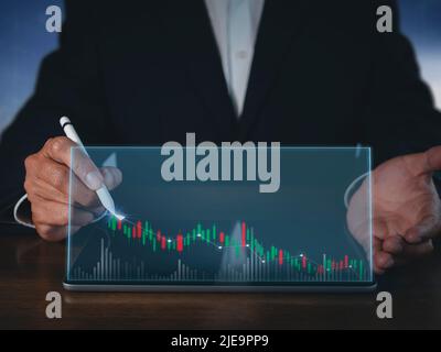 Homme d'affaires écrivant analyser graphique pour le marché boursier sur écran tablette. Graphique à dessin homme d'affaires graphique du stock de croissance. L'homme de main utilise le stylo pour Banque D'Images