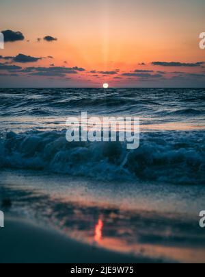 Lever de soleil coloré sur une plage des Caraïbes avec ciel nuageux et rayons de soleil avec réflexion de lumière sur le sable dans le parc national de sian Kaan près de Tulum Banque D'Images