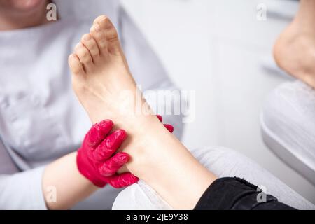 Gros plan sur un podiatre mains traitant les pieds pendant la procédure Banque D'Images