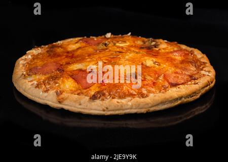 Pizza maison brûlée sur plateau dans four électrique, fond noir Banque D'Images