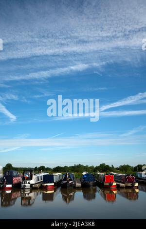 Des bateaux étroits amarrés dans un port de plaisance de Cheshire, dans un ciel bleu, avec des pistes de vapeur provenant des avions qui passent Banque D'Images