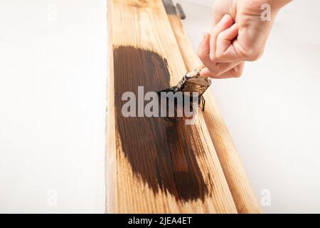 Un entrepreneur peint une porte en bois avec une brosse de vernis. Banque D'Images