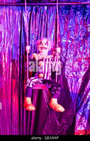 Une décoration clown effrayante dans une maison hantée pour Halloween balançant sur une balançoire. Banque D'Images