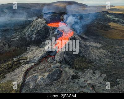 Paysage volcanique sur la péninsule de Reykjanes en Islande. Vue du cratère depuis le dessus. De la lave liquide s'écoule. Vapeur et fumée près du cratère. Banque D'Images