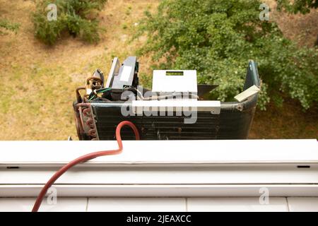 L'unité extérieure démontée du climatiseur pèse sur la rue dans l'appartement sous la fenêtre, la réparation et le diagnostic du climatiseur Banque D'Images