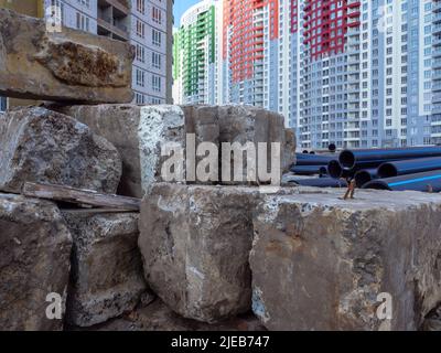 Un site de construction avec d'énormes blocs de béton et de grands tuyaux noirs en premier plan et de nouveaux bâtiments hauts en couleur en arrière-plan à Kiev Ukraine Banque D'Images