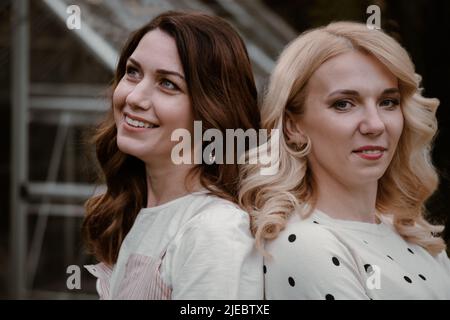 Deux sœurs matures dans le jardin le soir. Portrait d'une femme à ses 40s et 30s ans, parents, liens avec la nature sur la serre et les arbres Banque D'Images