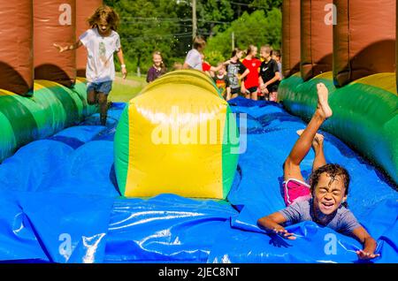 Les enfants jouent sur un toboggan aquatique gonflable, 27 juillet 2012, à Columbus, Mississippi. Banque D'Images