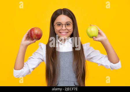 Fruits frais. Une adolescente tient des pommes sur fond de studio isolé jaune. Nutrition de l'enfant. Visage de fille heureux, émotions positives et souriantes. Banque D'Images