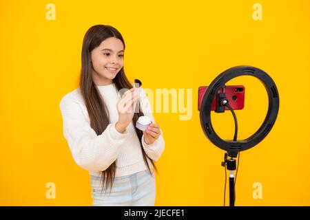 Une jeune fille blogger influenceur utiliser la lampe LED de selfie et smartphone sur trépied pour faire le tutoriel vidéo en ligne. Blog de beauté, présentation de cosmétiques de maquillage Banque D'Images