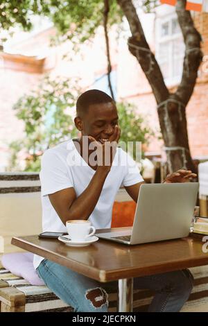 Souriant, riant et joyeux homme afro-américain couvrant son visage à la main dans la rue à l'extérieur. Nouvel emploi, entretien Banque D'Images