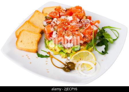 Tartare de saumon avec avocat servi avec toasts, arugula, citron et câpres Banque D'Images