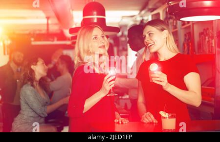 Deux jeunes femmes avec des cocktails qui s'amusent à la discothèque Banque D'Images
