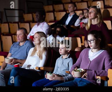 Adolescente avec parents et préadolescent frère regardant un film au cinéma Banque D'Images