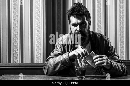 Un hipster brutal relaxant. Pub super endroit pour boire un verre et Amuse-toi bien. Hipster se détendre au pub. Homme avec barbe assis sur la table. Style de vie de week-end Banque D'Images