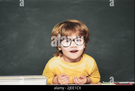 Petit garçon étudiant heureux avec une excellente marque. Mignon petit garçon d'âge préscolaire dans une salle de classe. Joli garçon avec une expression du visage heureux près du bureau avec Banque D'Images