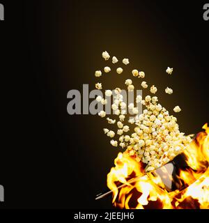 Pop-corn volant sur fond sombre. Pop-corn chaud volant de la casserole sous le feu. Concept publicitaire. Banque D'Images