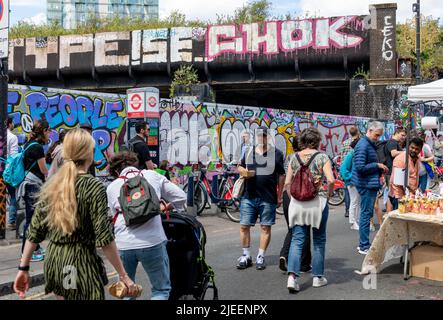 Londres. ROYAUME-UNI-06.26.2022. Une grande foule de touristes et de visiteurs dans le marché de Brick Lane visitant les stands de nourriture de rue. Banque D'Images