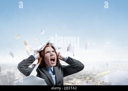 Jeune femme stressée déchirant des documents avec une expression faciale frustrée. Banque D'Images