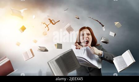 Jeune femme stressée déchirant des documents avec une expression faciale frustrée. Banque D'Images