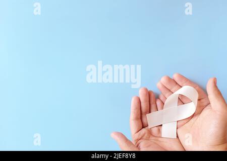 Vue de dessus du ruban de sensibilisation blanc de couleur pour tenir la main. SCID, concept de prévention et de soins de sensibilisation au cancer des os et des poumons. Banque D'Images