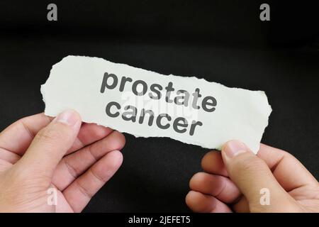 Concept de diagnostic du cancer de la prostate. Papier tenant à la main avec texte écrit sur fond noir foncé. Banque D'Images