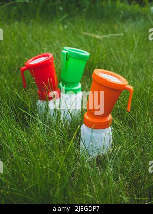 Trois tasses à trempette de couleur pour le bétail sur l'herbe, mise au point sélective. Concept d'hygiène et de désinfection du pis de la vache. Soins de santé de pis avant Banque D'Images