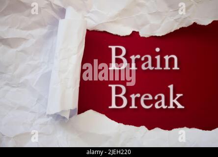 Brain Break texte avec un livre blanc déchiré et froissé sur fond coloré. Banque D'Images