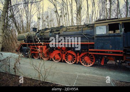 Locomotive à vapeur garée à un terminal. Chemin de fer historique de 1940 en rouge noir. Photo de nostalgie de la technologie passée Banque D'Images