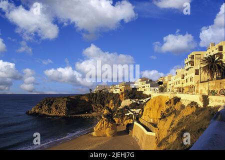 Les appartements, lumineux tôt le matin sous un ciel bleu profond, donnent sur l'extrémité ouest déserte de la plage principale à Albufeira, Algarve, Portugal Banque D'Images