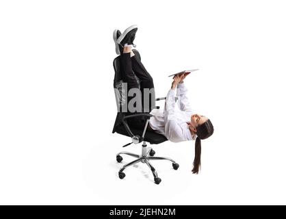 Femme d'affaires couchée sur une chaise, travaillant sur une tablette isolée sur fond blanc de studio Banque D'Images