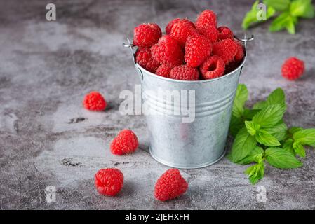 Framboises dans le petit seau Banque D'Images