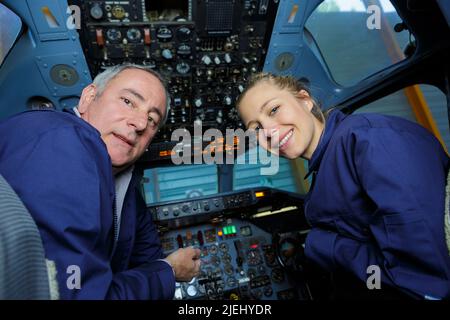 homme âgé et jeune femme portant une combinaison dans le cockpit de l'avion Banque D'Images